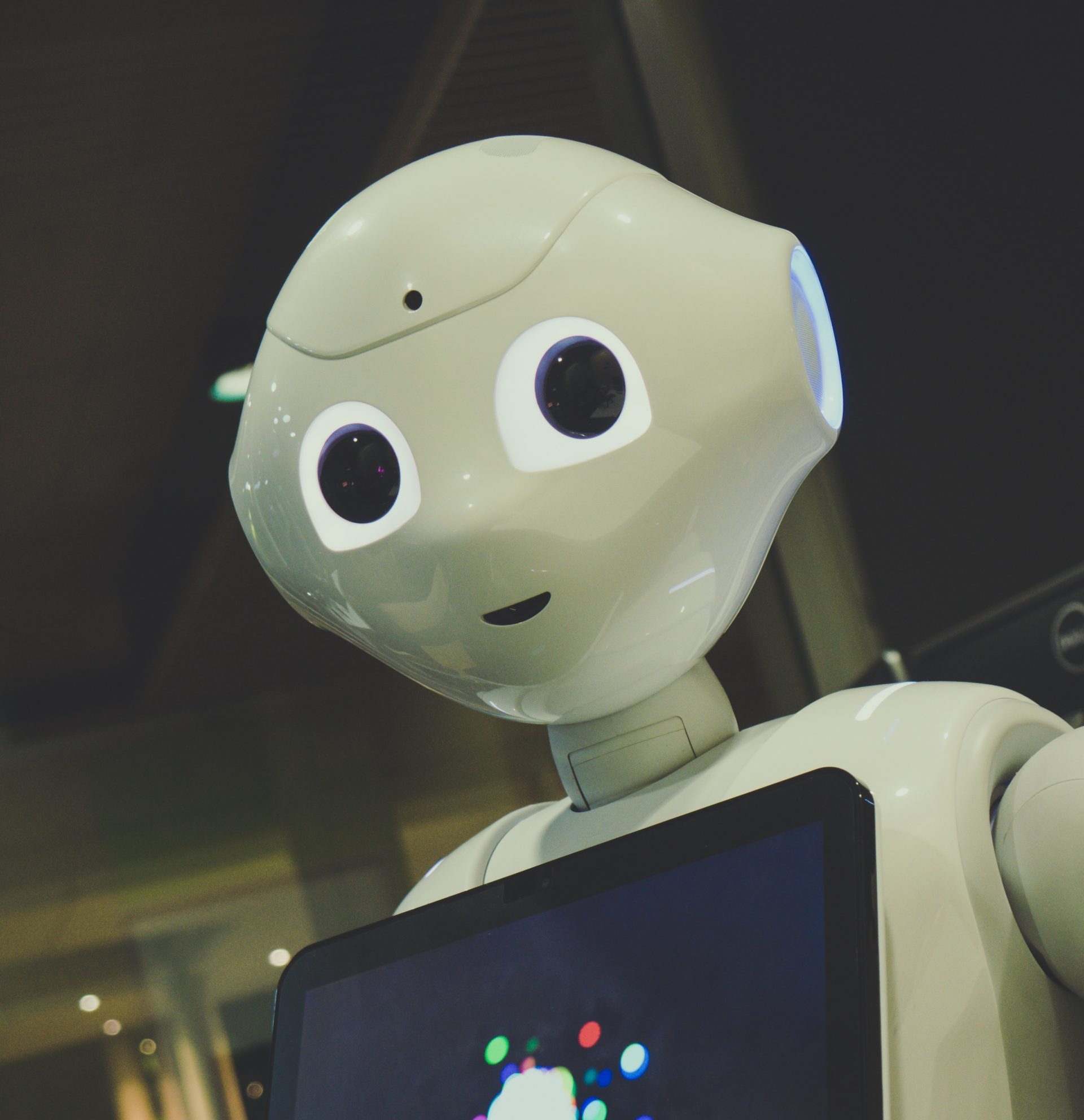 white robot toy holding black tablet